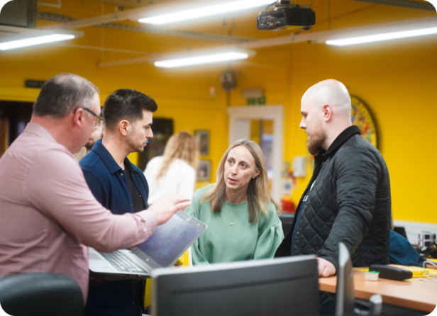A team of Webmarteers talk around a laptop in Webmart's head office