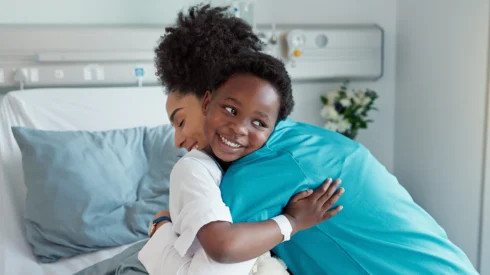 a doctor hugs a child in a hospital bed at Great Ormond Street Hospital