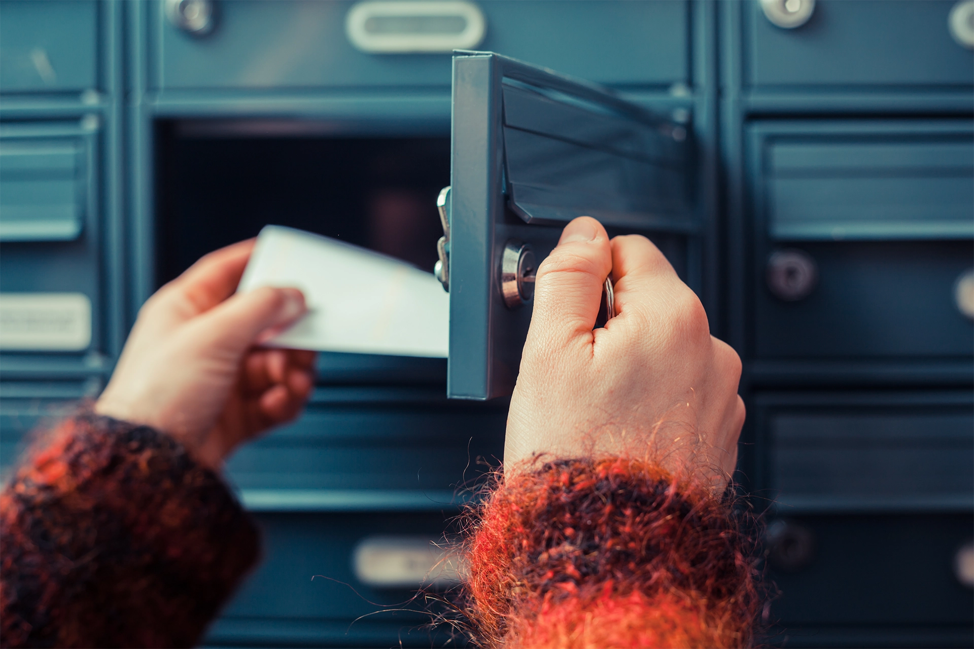 Hands open a mail box and pulls out a piece of direct mail marketing