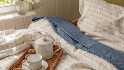 Piglet in Bed campaign image shows a bed made with luxury bed sheets and a tray with a teapot and cup on