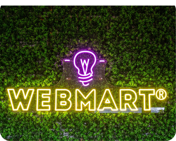 Image of neon Webmart logo sign against a plant backdrop.