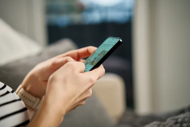 A hand holds a mobile phone and browses an online retailers website.