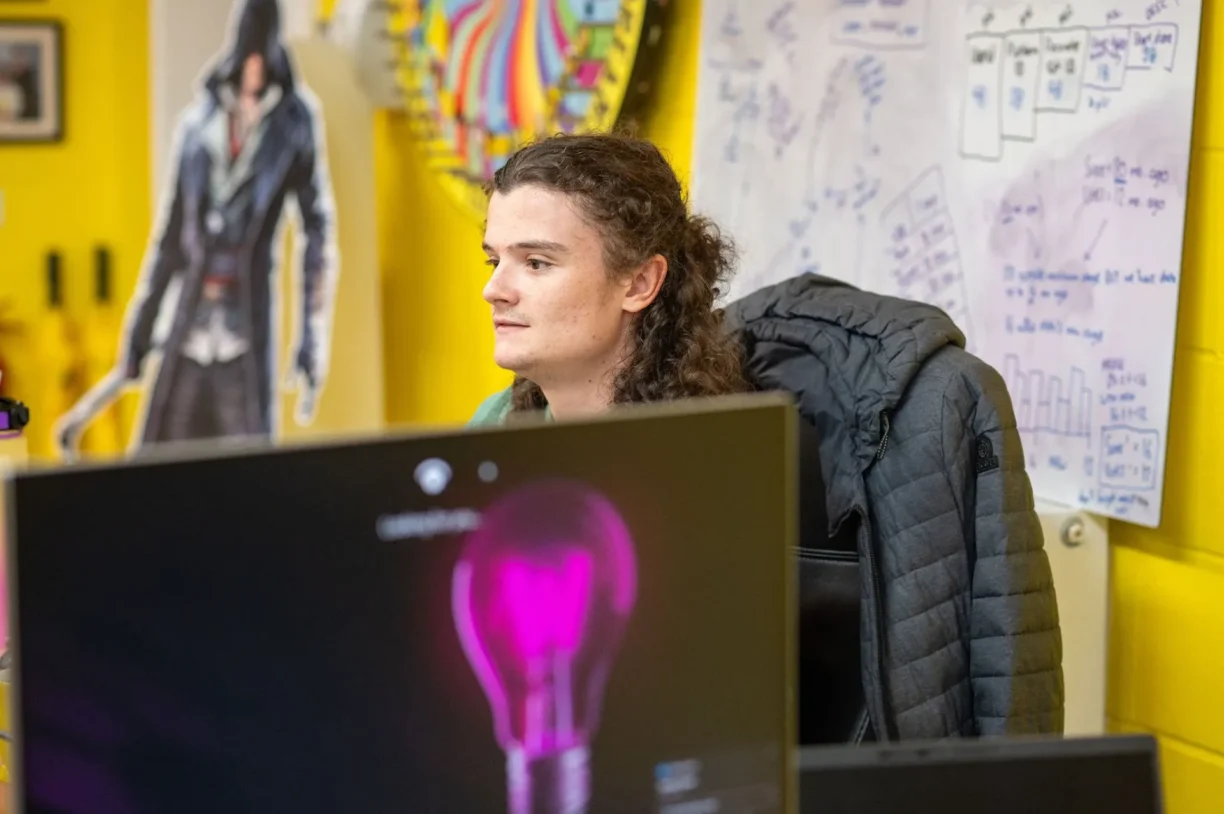 Image of Webmart employee working while a whiteboard with workshop strategy sits in the background.