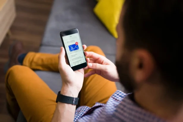A person holds a mobile phone with an email marketing notification pop up with an email notification.