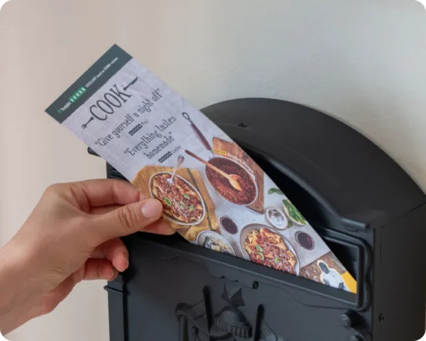 'COOK' Print leaflet being placed in into a letterbox - mail marketing expertise by Webmart.
