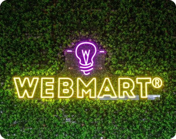 Webmart neon sign logo on a faux living wall backdrop
