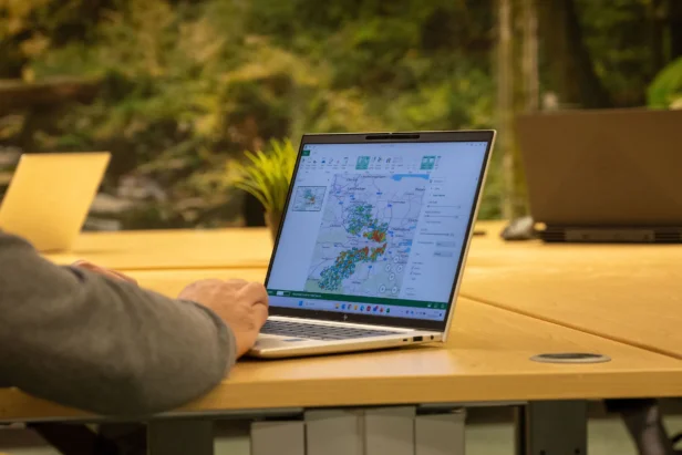 A Webmarteer works on a laptop which shows a map of the UK and hotspots to highlight the postcode areas for a data targeted mail marketing campaign