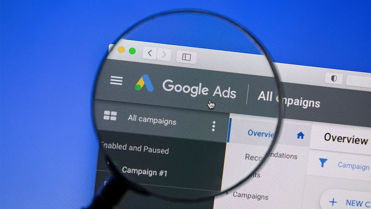 A magnifying glass highlights the Google Ads logo on the ads dashboard. PPC advice from search marketing agency, Webmart.